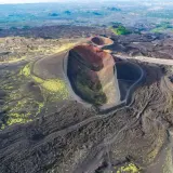 Vista aerea dei crateri spenti del vulcano Etna, con sentieri che si snodano tra la lava nera e la vegetazione gialla. Un'emozionante visita al Monte Etna.