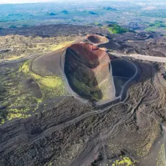 Vista aerea dei crateri spenti del vulcano Etna, con sentieri che si snodano tra la lava nera e la vegetazione gialla. Un'emozionante visita al Monte Etna.