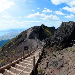 Sentiero sul cratere del Vesuvio, un vulcano attivo. Scale di legno e corde guidano i visitatori verso la cima, con vista sul golfo.
