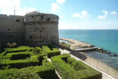 Castello Aragonese e giardini curati, un'idea di cosa vedere a Taranto in mezza giornata, con il mare azzurro sullo sfondo.
