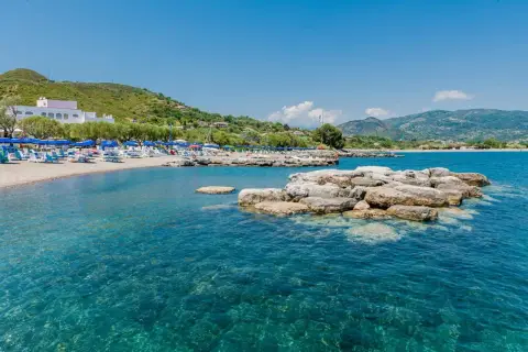 Spiaggia attrezzata con ombrelloni e lettini, mare cristallino e rocce affioranti. Un angolo di paradiso nel Cilento, mare da sogno.