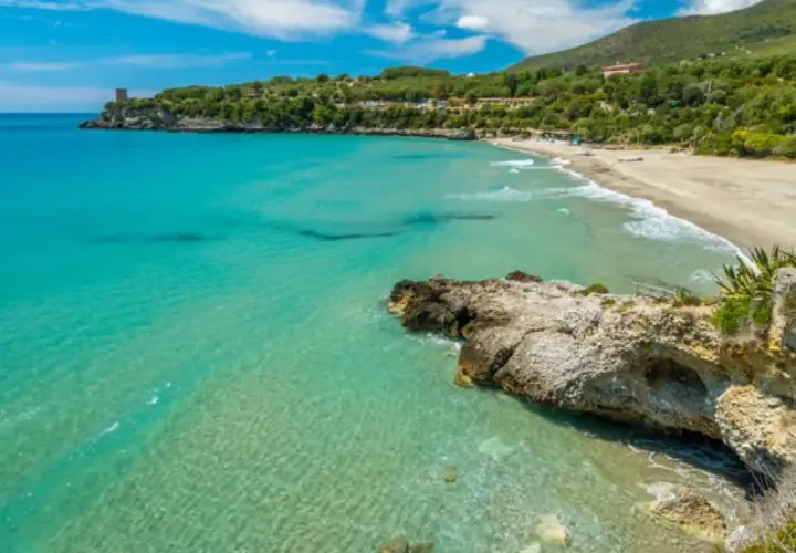 Acque cristalline e una spiaggia dorata incorniciano la **costiera cilentana**, con una torre antica a guardia del mare.