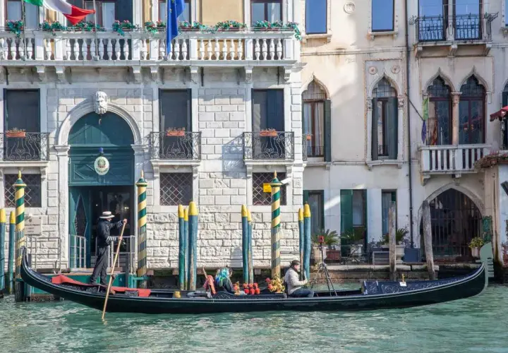 Gondola a Venezia, perfetta per un itinerario di un giorno. Un gondoliere guida la barca lungo un canale, con palazzi storici sullo sfondo.