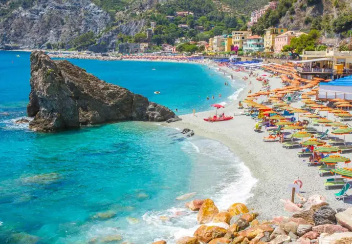 La monterosso spiaggia libera è affollata di ombrelloni colorati e bagnanti che si godono il sole e il mare cristallino.