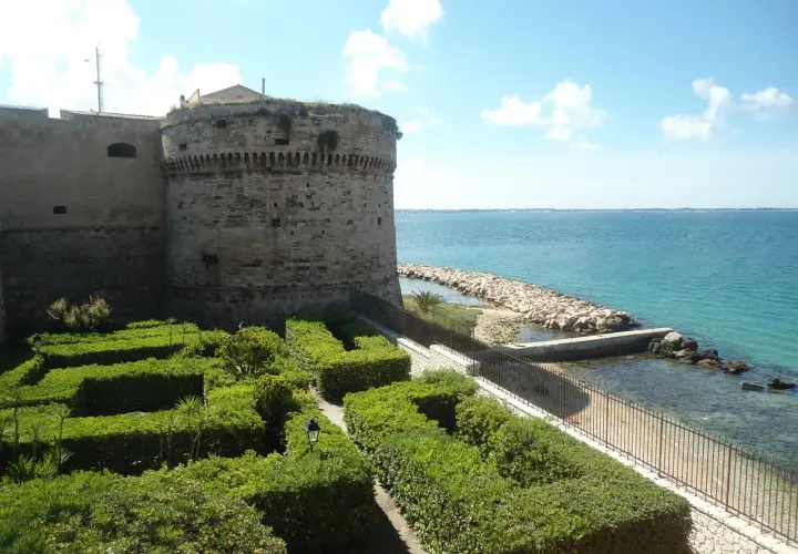 Castello Aragonese e giardini curati, un'idea di cosa vedere a Taranto in mezza giornata, con il mare azzurro sullo sfondo.