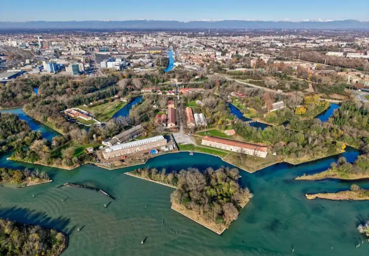 Marghera: cosa vedere? Un'area verde con canali, edifici storici e la città sullo sfondo.