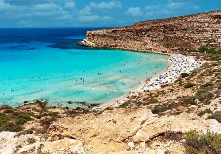 Spiaggia con acque cristalline e scogliere, un vero gioiello per la classifica delle spiagge più belle del mondo.