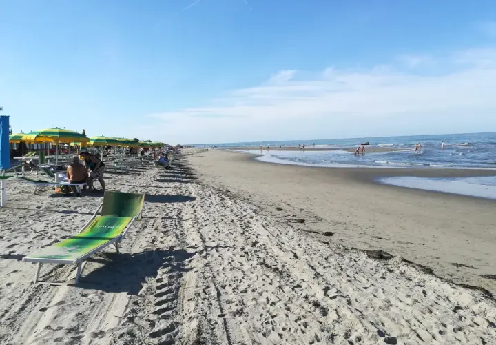 Una giornata di sole sulla spiaggia del Veneto. Ombrelloni colorati, lettini e il mare azzurro invitano al relax.