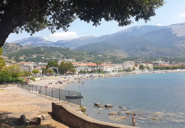 Vista panoramica di Sapri con la sua spiaggia affollata, il mare azzurro e le montagne sullo sfondo. Un luogo ideale per scoprire cosa vedere a Sapri.