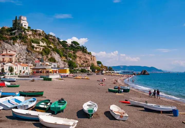Spiagge Vietri sul Mare con barche sulla sabbia scura e case aggrappate alla scogliera.