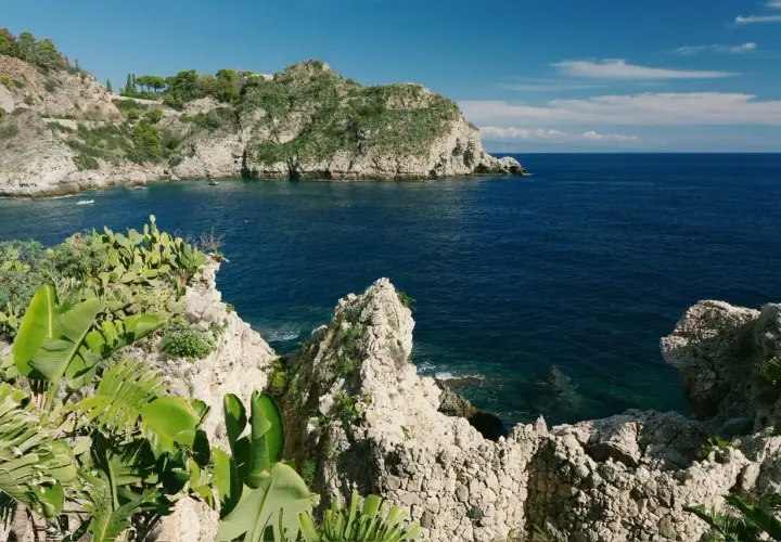 Scogliera verdeggiante e mare blu intenso al lido Isola Bella Taormina.