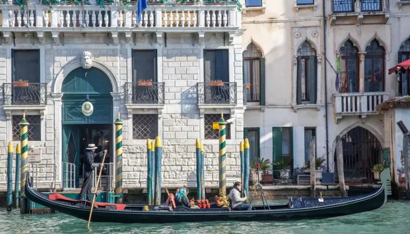 Gondola a Venezia, perfetta per un itinerario di un giorno. Un gondoliere guida la barca lungo un canale, con palazzi storici sullo sfondo.