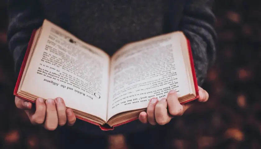 Mani che tengono un libro aperto con testo in inglese, forse uno dei tanti libri premiati che raccontano storie avvincenti.