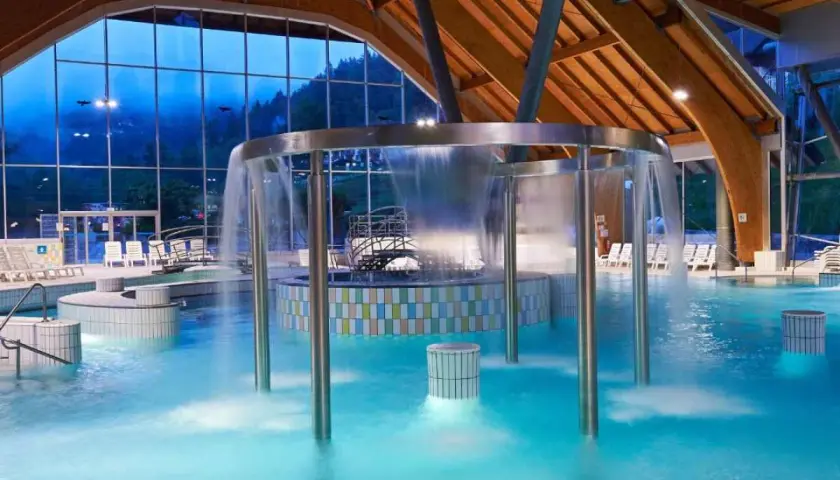 Piscina interna con cascata, lettini e vista sulle montagne. Un luogo ideale per rilassarsi nelle terme in Slovenia vicino al confine italiano.