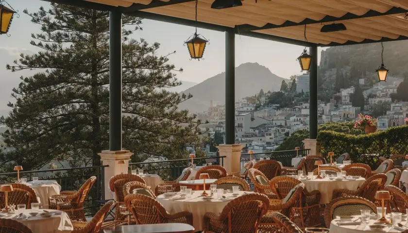 Terrazza con tavoli apparecchiati e vista su Taormina. Un luogo perfetto per un aperitivo al bar Timeo Taormina.