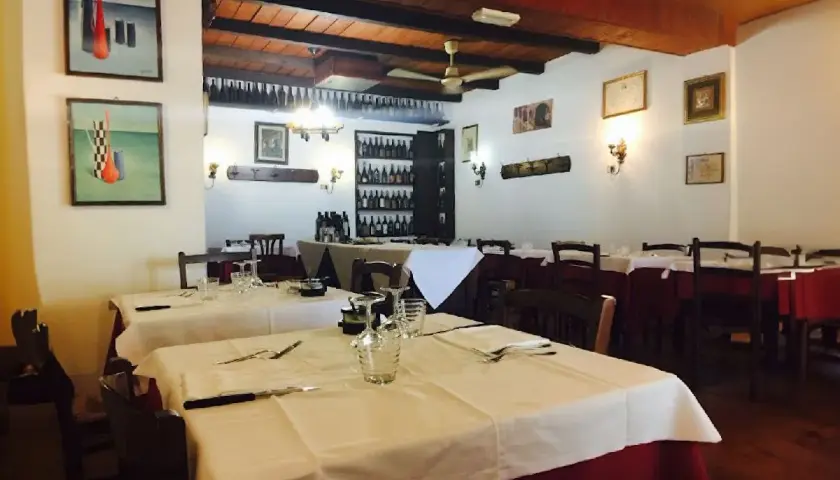 Interno di uno dei ristoranti di Ferrara, con tavoli apparecchiati e quadri alle pareti.