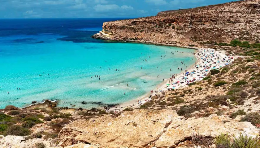 Spiaggia con acque cristalline e scogliere, un vero gioiello per la classifica delle spiagge più belle del mondo.