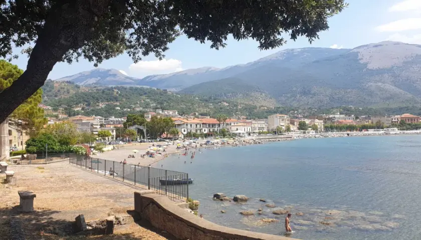 Vista panoramica di Sapri con la sua spiaggia affollata, il mare azzurro e le montagne sullo sfondo. Un luogo ideale per scoprire cosa vedere a Sapri.