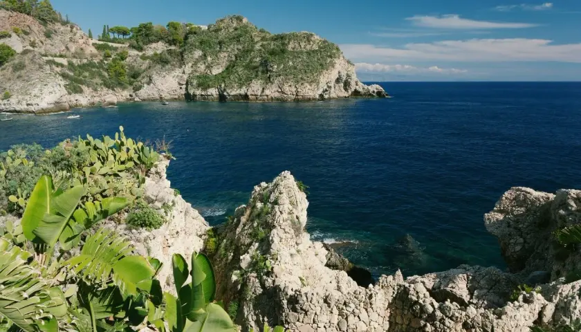 Scogliera verdeggiante e mare blu intenso al lido Isola Bella Taormina.