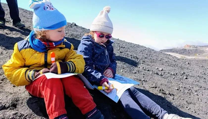 Bambini vestiti a strati, con cappelli e giacche, imparano come vestirsi per andare sull'Etna.