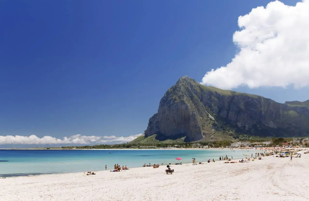 Spiaggia di San Vito Lo Capo, un vero paradiso di **Palermo mare senza auto**. Acque cristalline, sabbia bianca e la maestosa montagna di Monte Monaco.