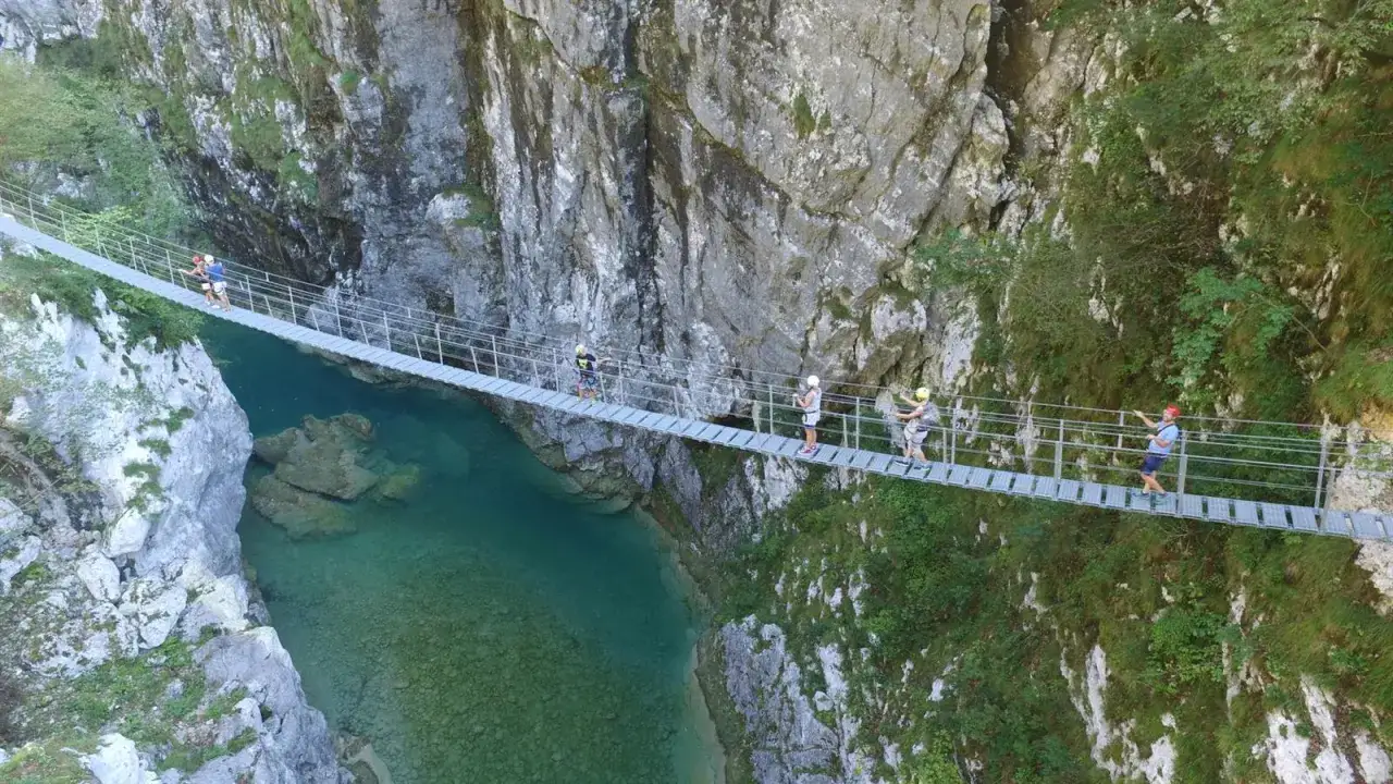 Persone su un ponte sospeso sopra il fiume turchese in Val Cellina, Barcis. Un'avventura mozzafiato tra le rocce.
