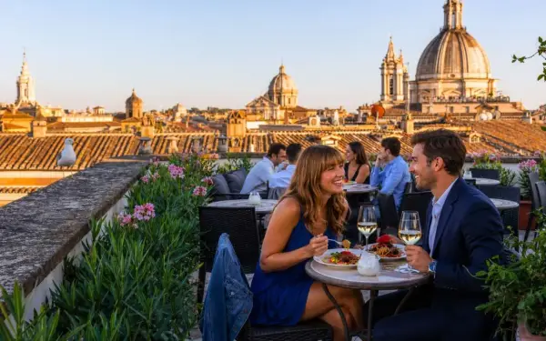 Coppia felice cena in uno dei ristoranti con vista Roma, con cupole e tetti all'orizzonte.