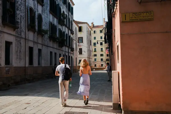 Coppia passeggia in una stretta via di Venezia, una delle più belle città da visitare nel nord Italia.