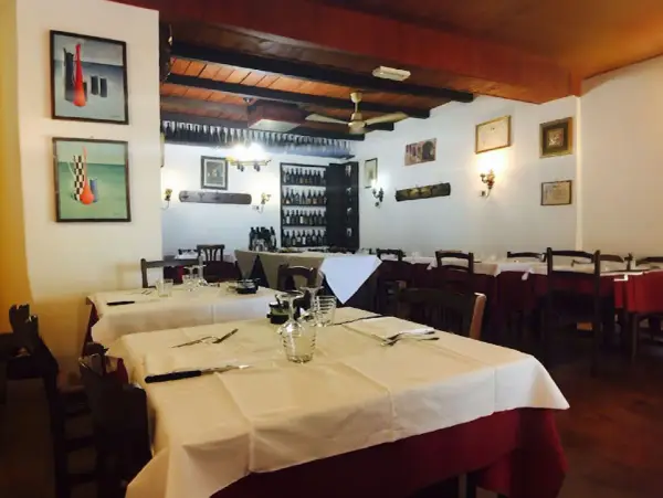 Interno di uno dei ristoranti di Ferrara, con tavoli apparecchiati e quadri alle pareti.